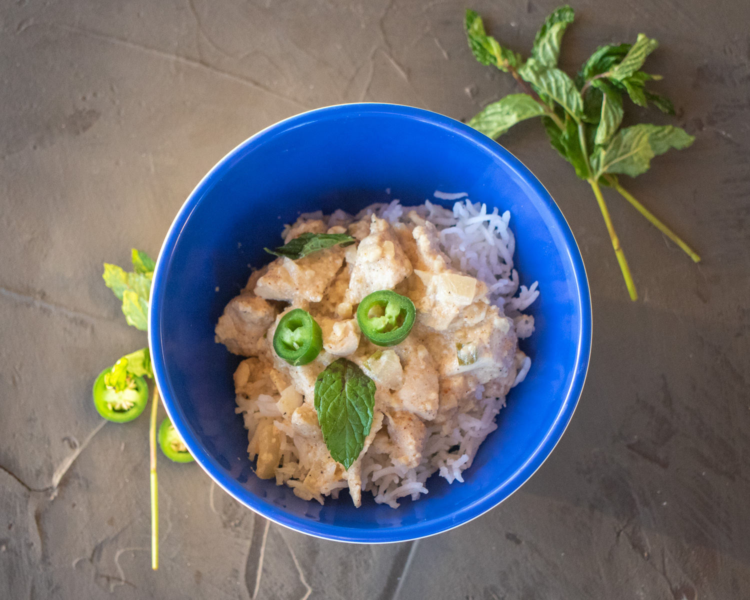 White Chicken Korma in a blue bowl surrounded by mint leaves