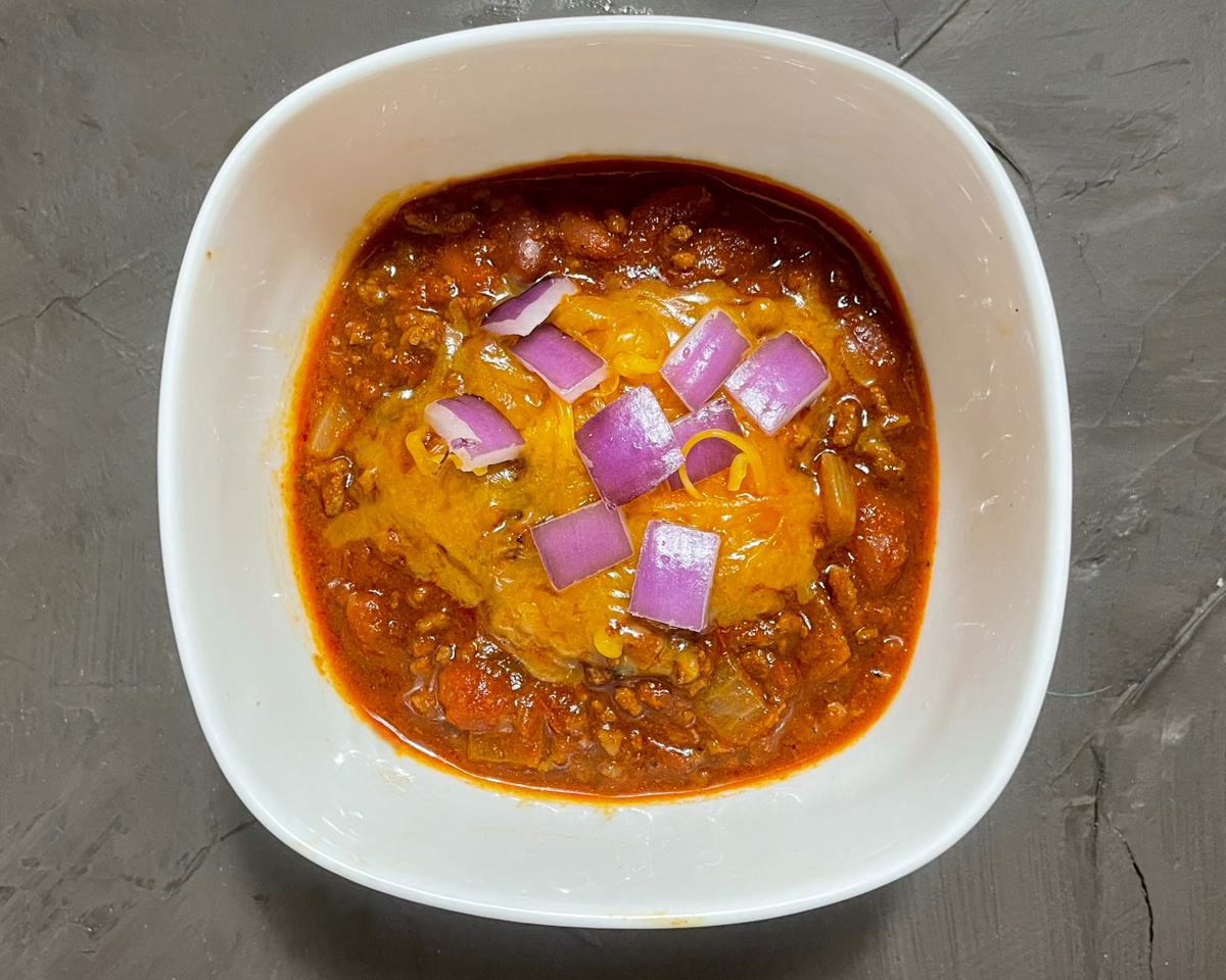 chili served in a bowl with cheese and onions