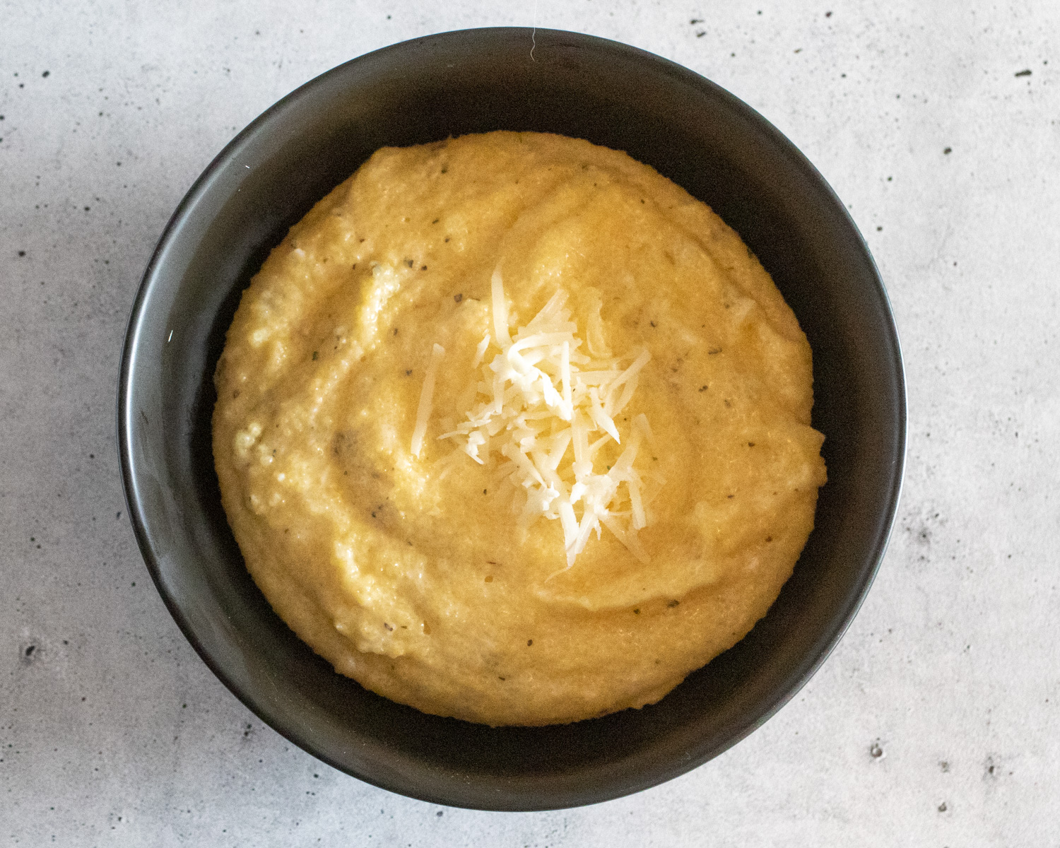 Asiago Cheese Grits served in a gray bowl and garnished with additional cheese