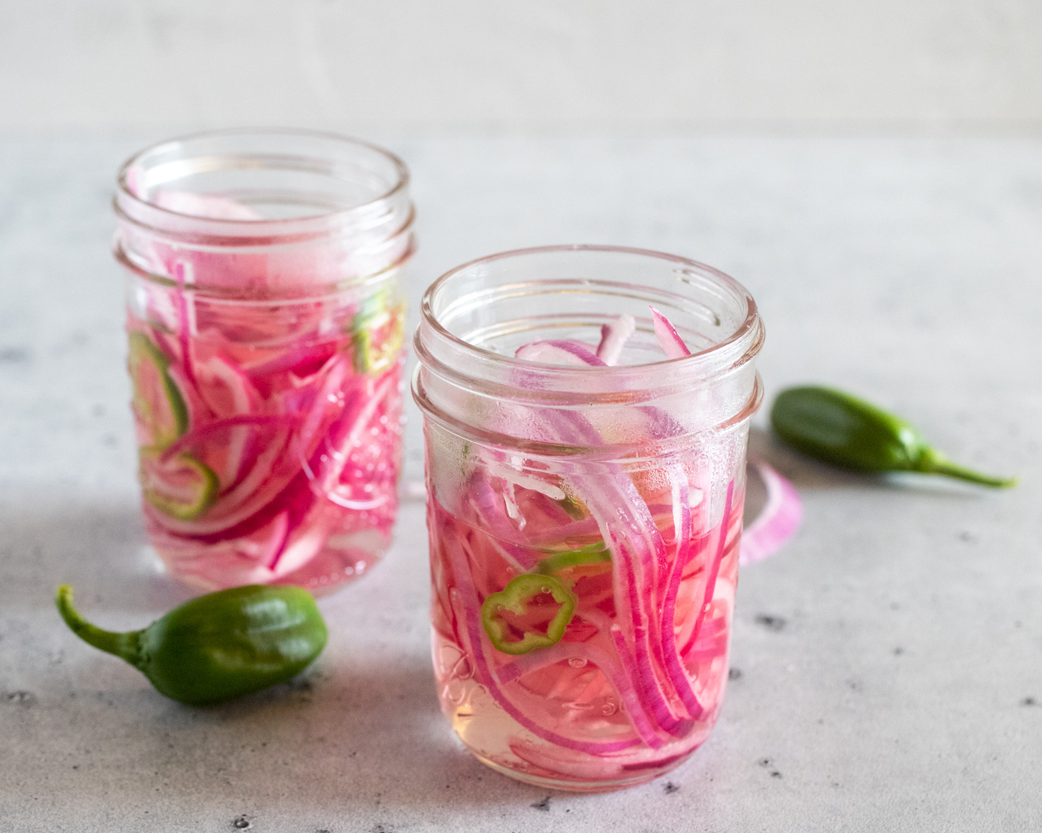 Slice onion and peppers in a mason jar after having poured hot vinegar and water over top.