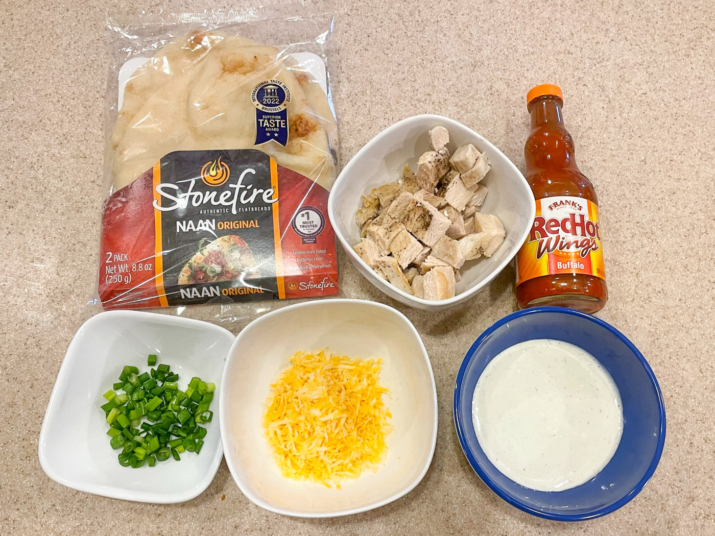 Ingredients to make Buffalo chicken flatbread, arranged on counter