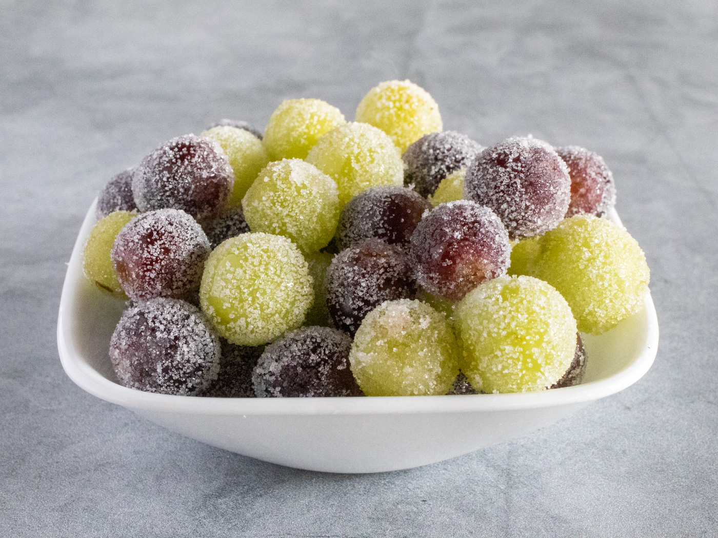 Candied green and red grapes in a white bowl