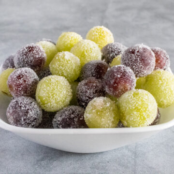 Candied green and red grapes in a white bowl