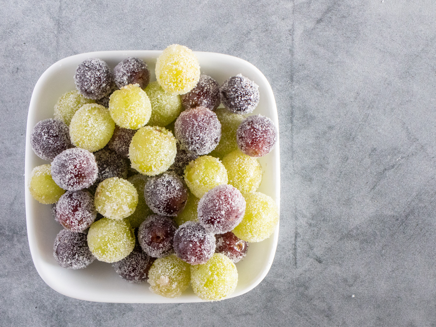 Candied green and red grapes in a white bowl