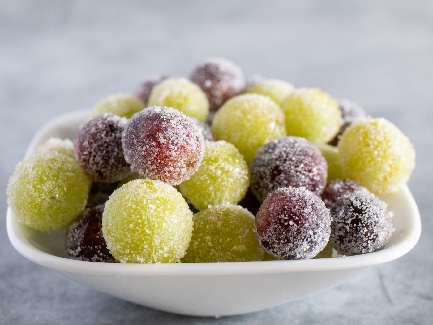 Candied green and red grapes in a white bowl