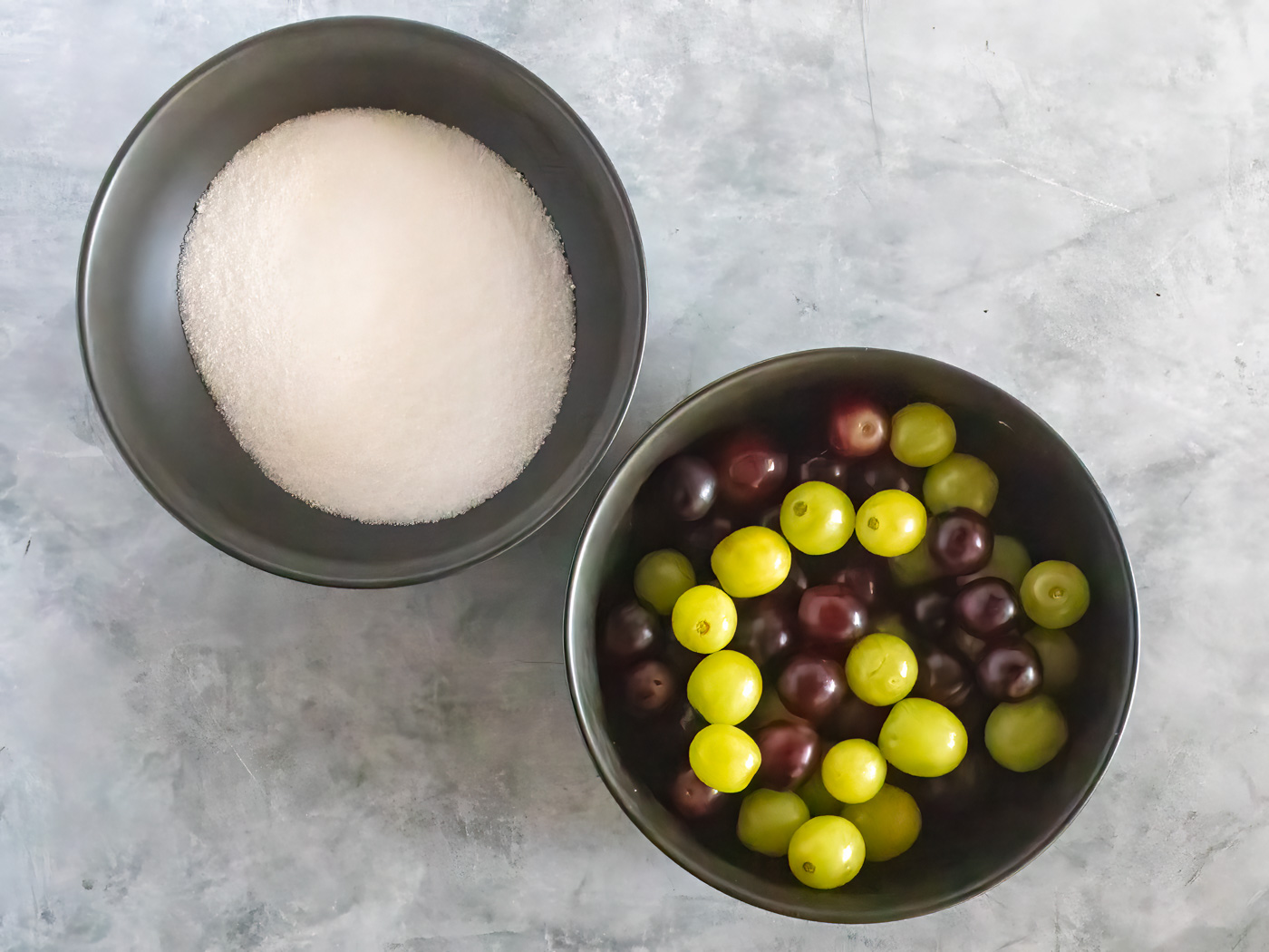 Candied grape ingredients - white sugar in one bowl, fresh grapes in another