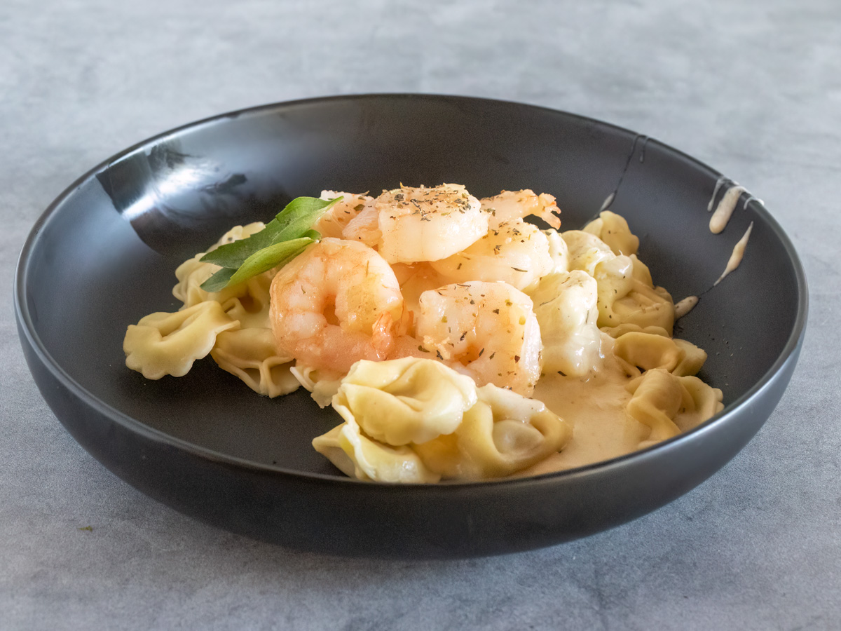 finished shrimp tortellini alfredo in a black bowl