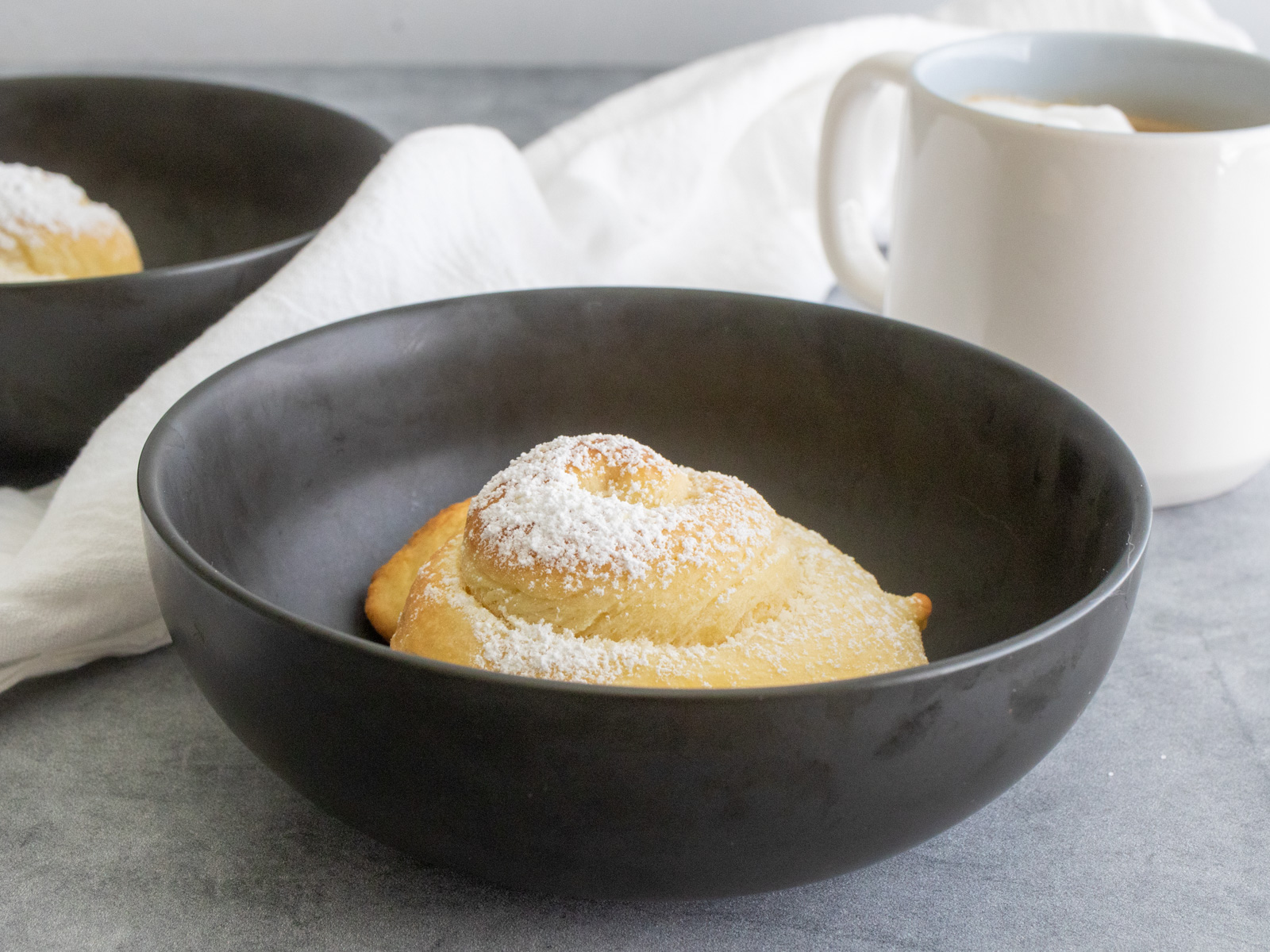 Pan de Mallorca roll in a bowl, with a cup of coffee.