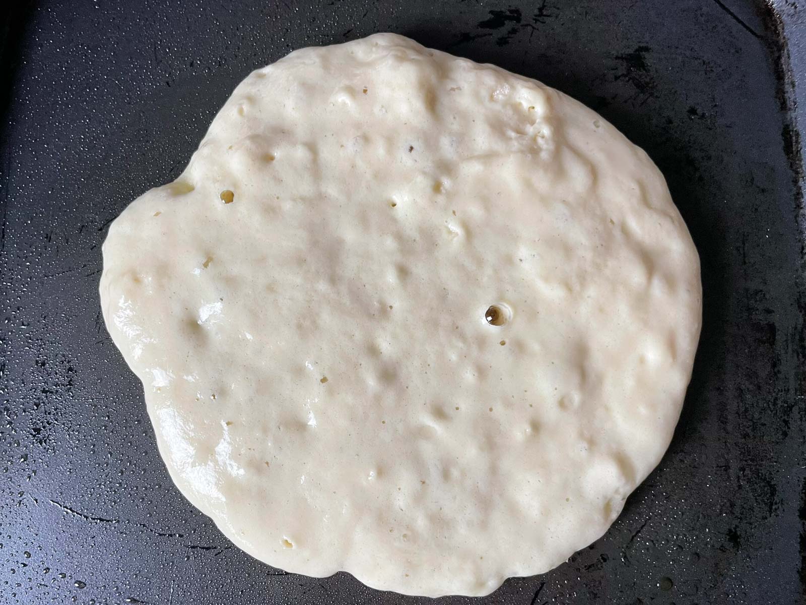 A pancake that is starting to bubble while being cooked, and is ready to be flipped
