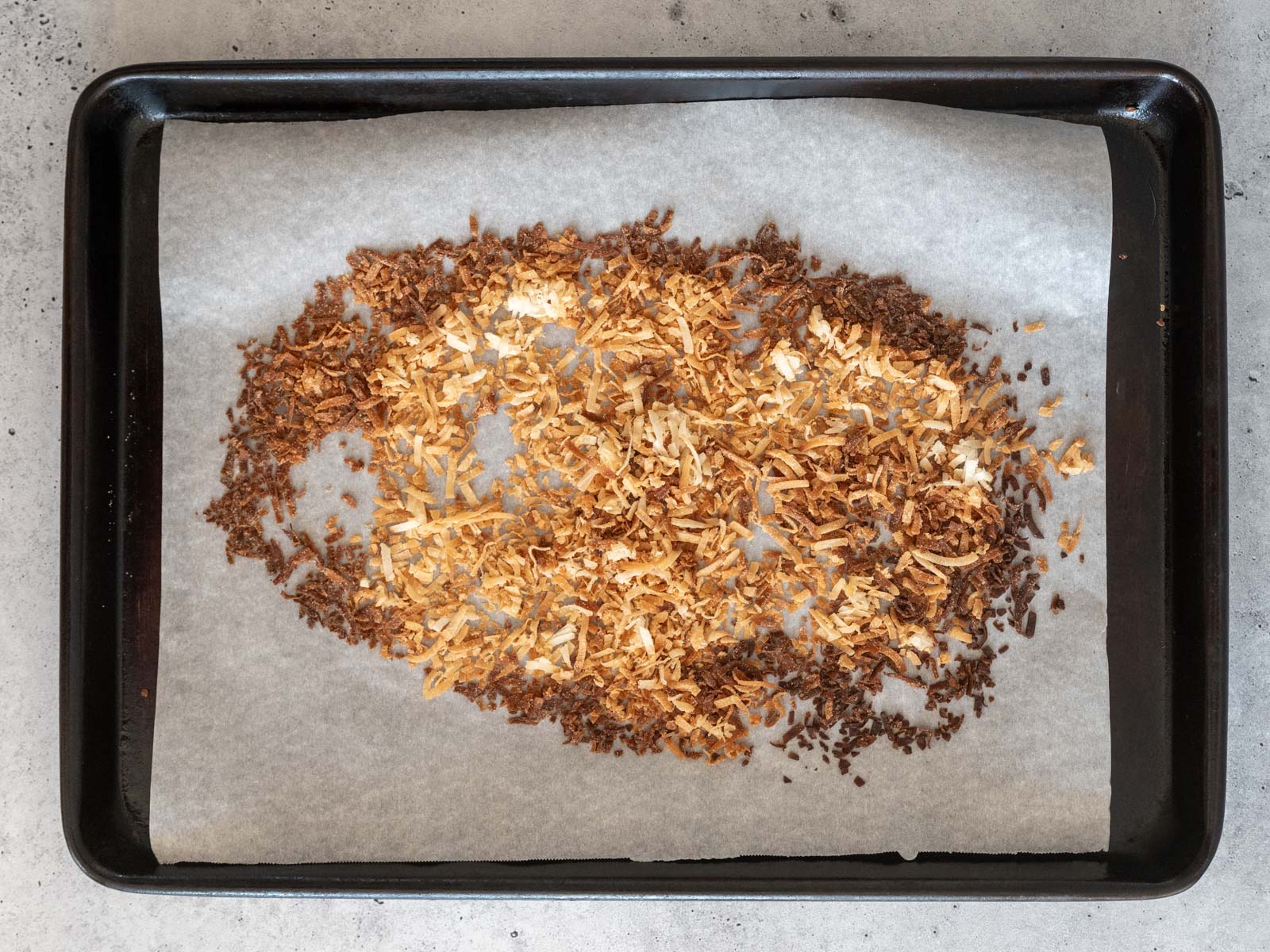 Sweetened coconut flakes after toasting in the oven, spread on a baking sheet with parchment paper